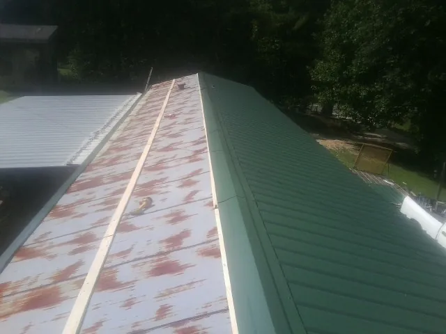 Old rusted panels beside newly installed green metal roofing — Wind Damage Roof Repair by Roofing Brothers in Lakeland