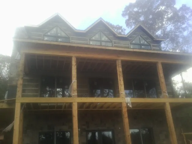 Dormers and porch framing on a large log home under construction — Roof Coating work by our crew in Lakeland